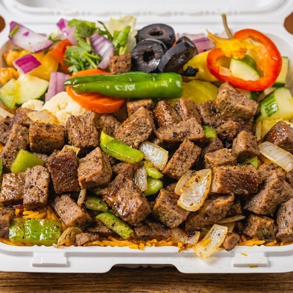 A takeout container filled with seasoned beef, rice, and a colorful salad with olives and peppers.